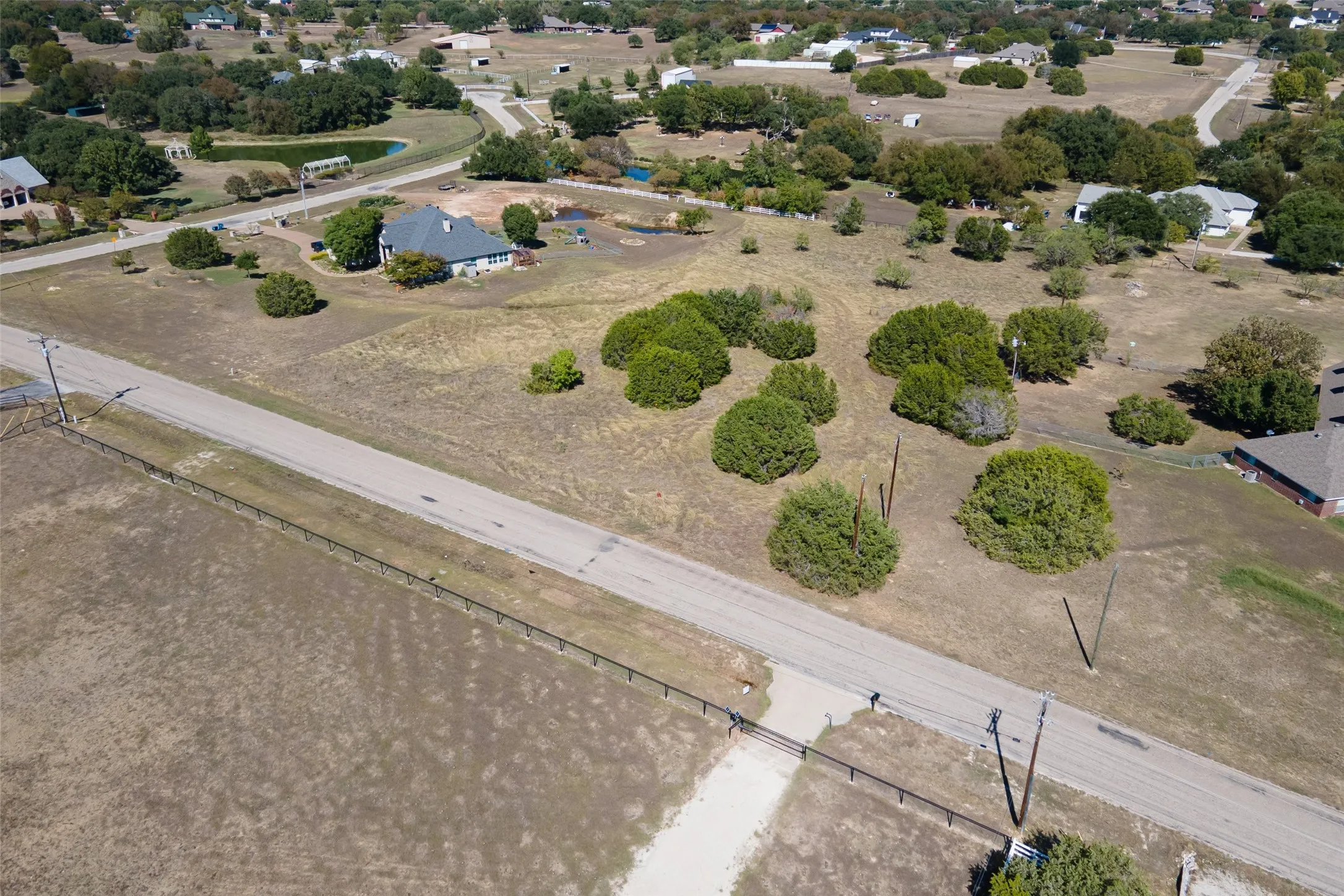 Expansive land parcel with direct road frontage, perimeter fencing, and mature trees