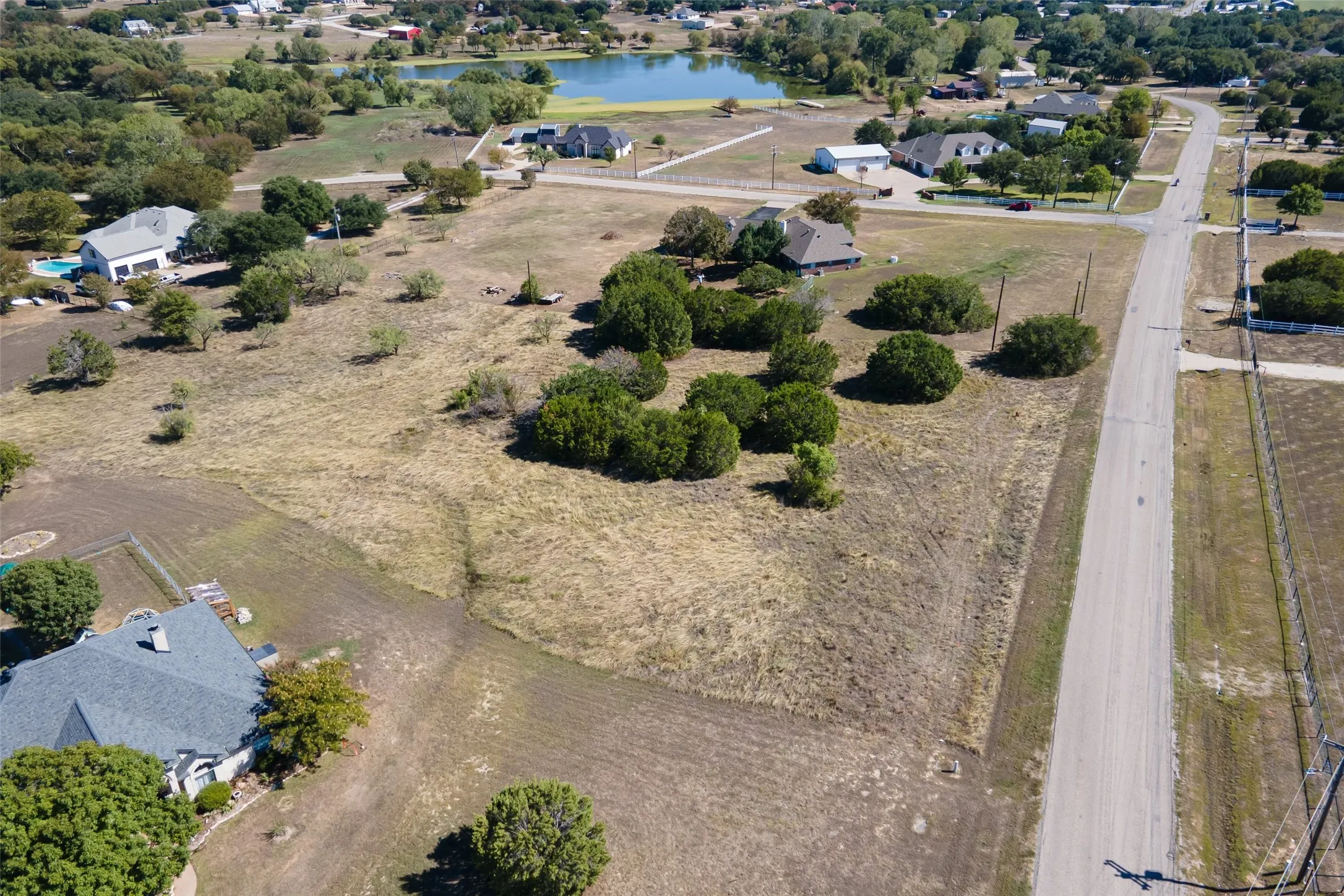 Expansive undeveloped land with scattered trees, bordered by a paved road