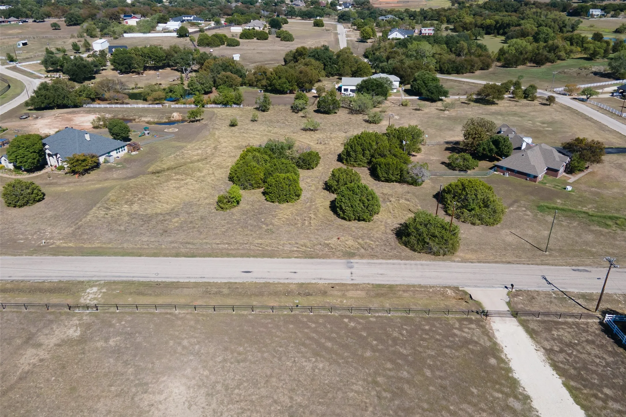 Expansive land parcel featuring existing road frontage and scattered mature trees