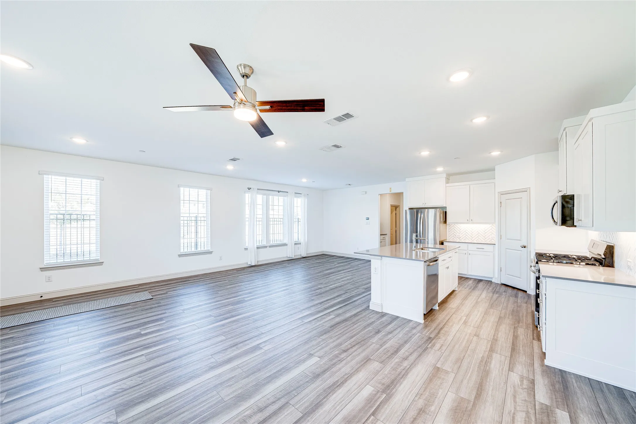 Open-concept living space featuring wood-finish flooring, recessed lighting, and a ceiling fan