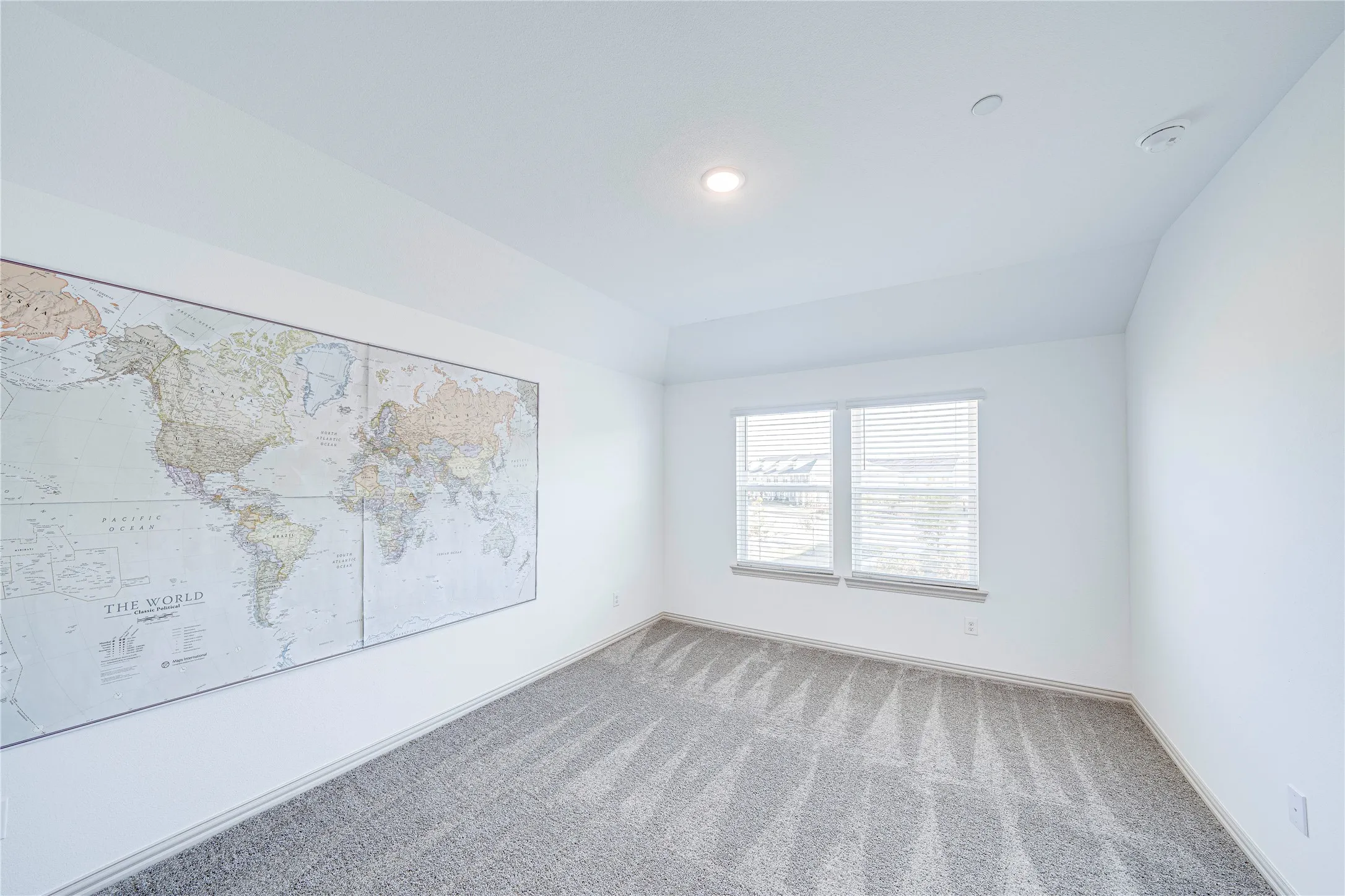 White interior walls, recessed lighting, and a window with blinds