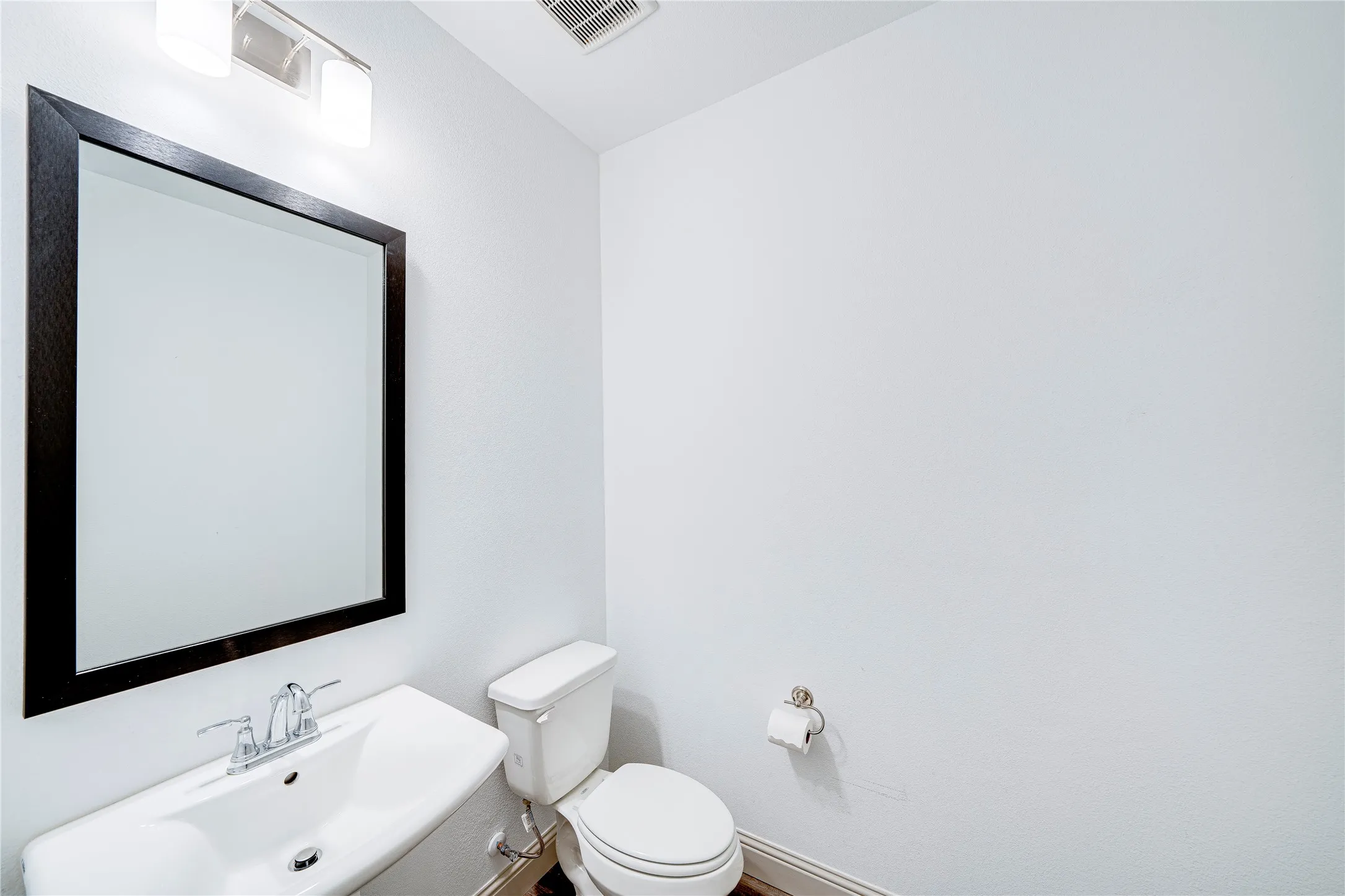Wall-mounted vanity with a rectangular sink, chrome faucet, and framed mirror
