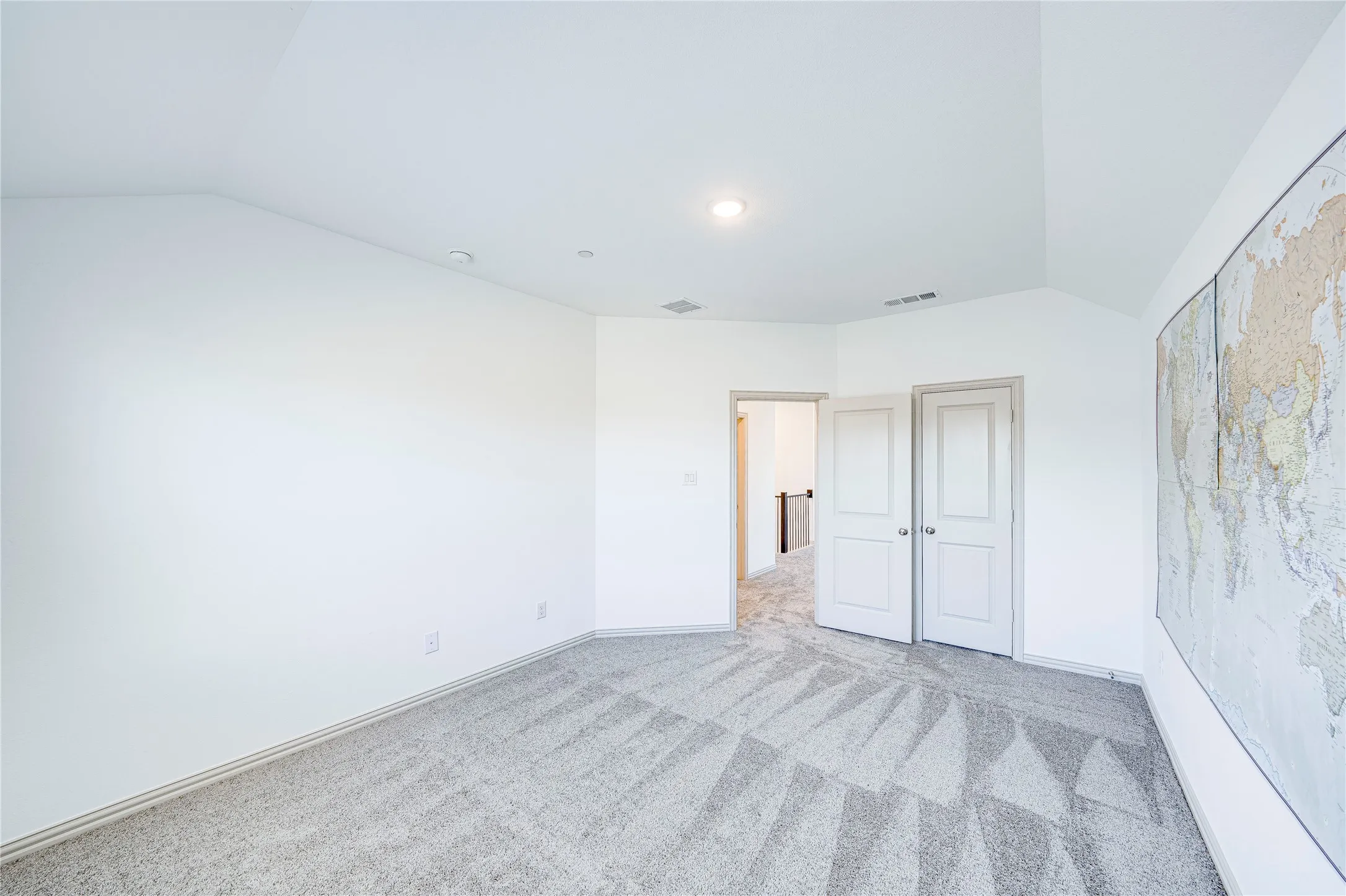Vaulted ceiling, recessed lighting, neutral tone carpeting, white panel doors, and bright white wall finishes