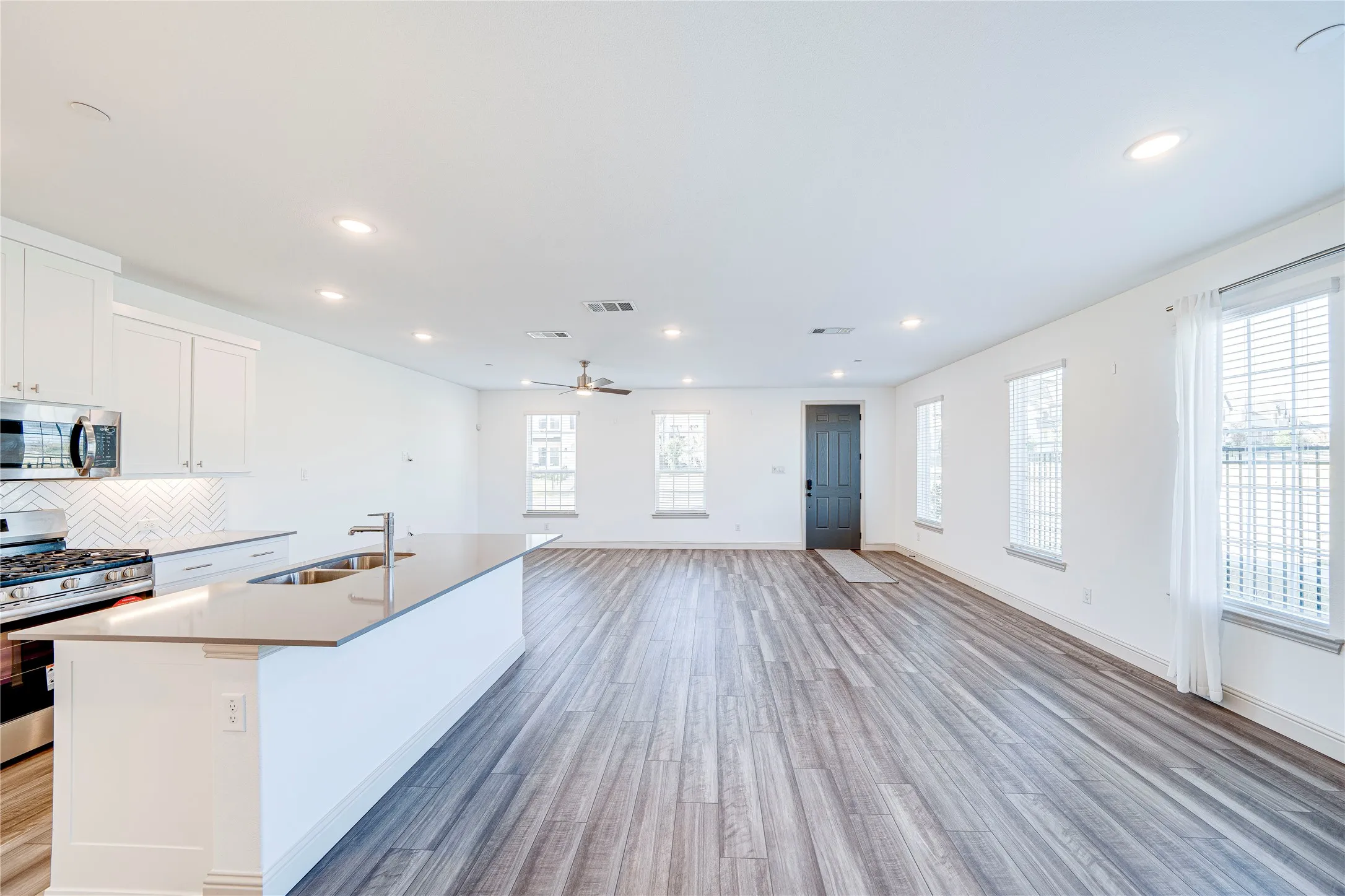 Expansive open-concept living area featuring wood-finish flooring, recessed lighting, and a ceiling fan