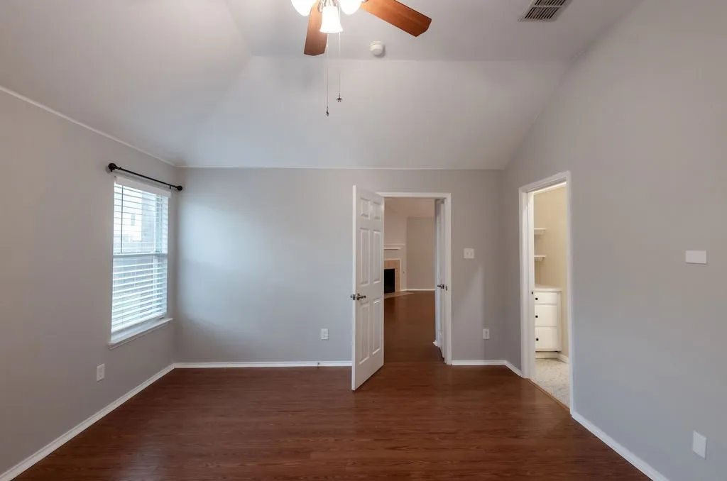 Vaulted ceiling, wood-finish flooring, ceiling fan, white paneled doors, and built-in cabinetry