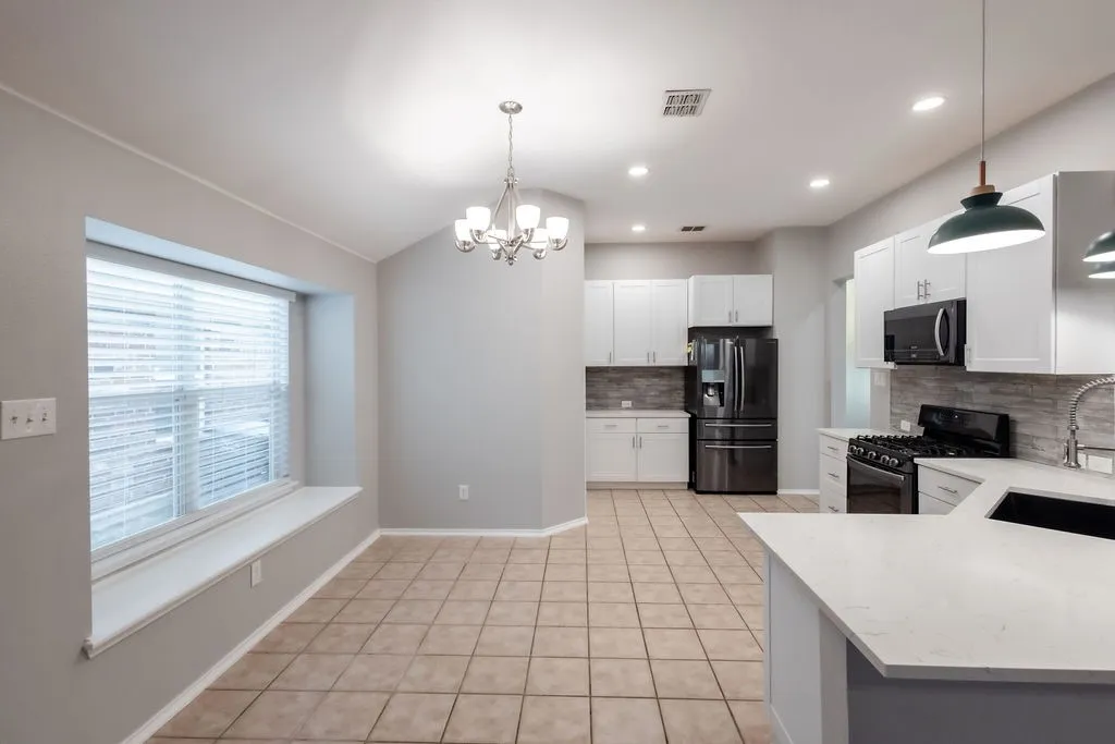 Contemporary kitchen featuring light cabinetry, stainless steel appliances, a white countertop, and a tiled backsplash