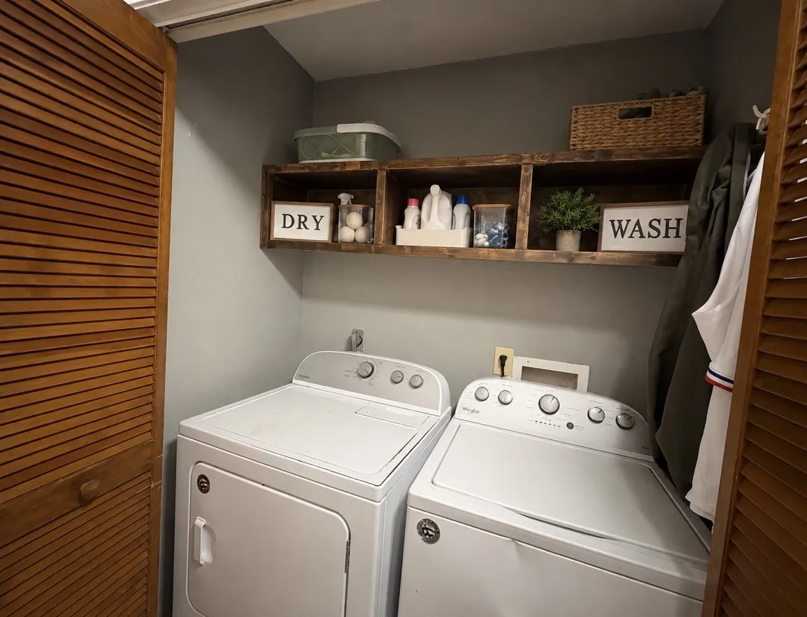 Built-in wooden shelving above laundry appliances provides convenient storage