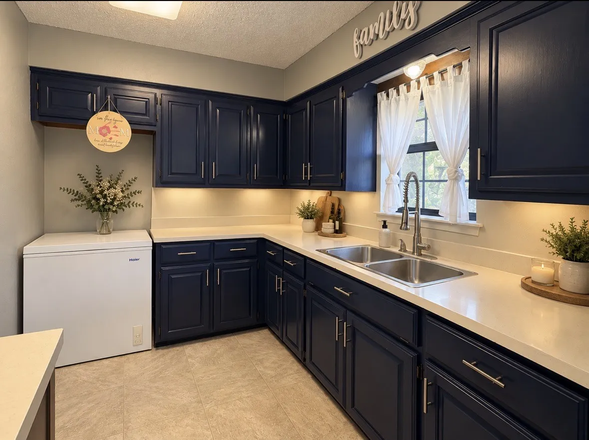 Navy blue cabinetry with brushed nickel hardware, light-toned countertops, a double basin stainless steel sink, and a modern pull-down faucet