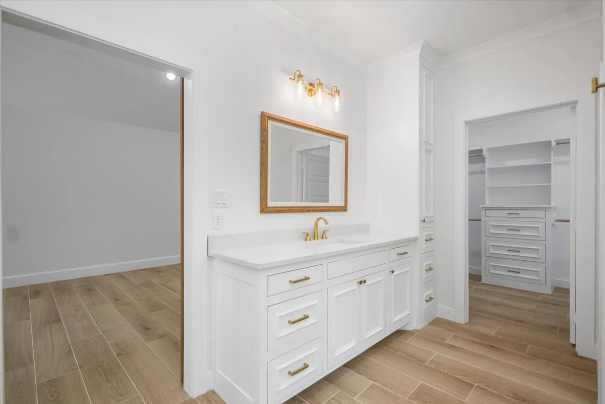 White vanity with gold-tone hardware and single basin sink