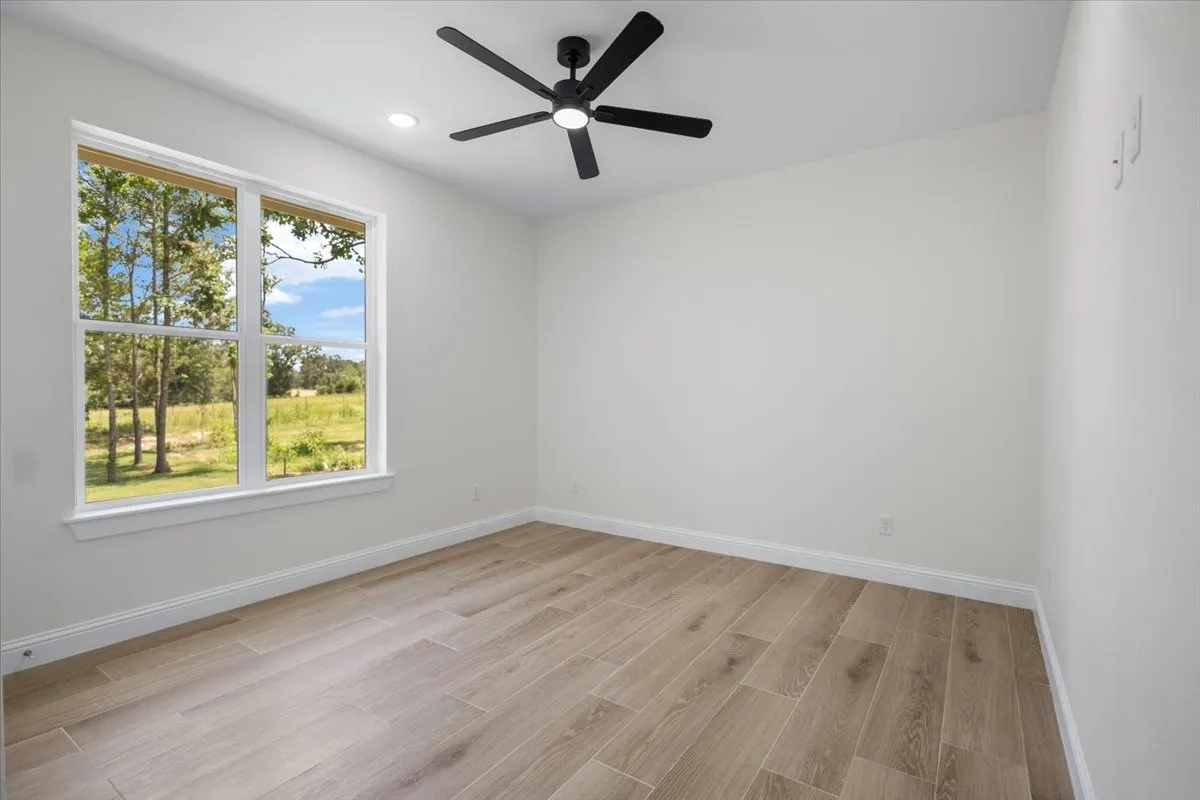 Wood-finish flooring, white walls, and a large window with white trim