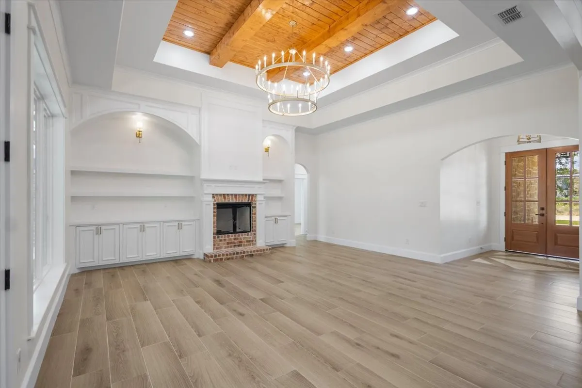 Vaulted ceiling with wood-finish beams, recessed lighting, and a chandelier