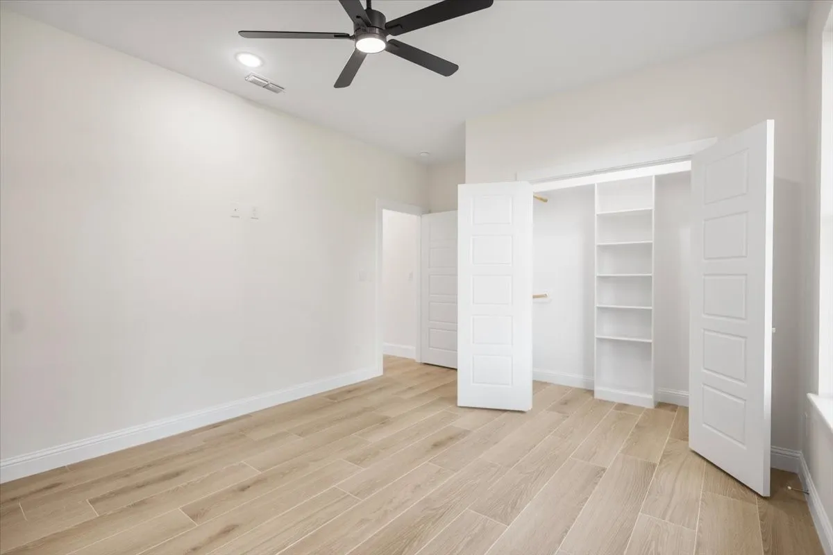 Wood-finish flooring, recessed lighting, ceiling fan, built-in shelving, and white panel doors