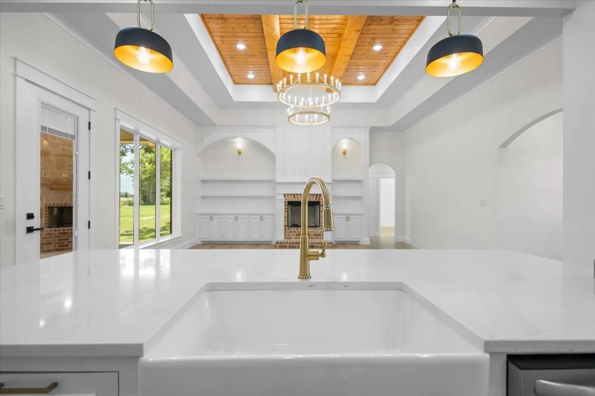 Spacious interior featuring a white farmhouse sink, white countertops, and a gold-finish faucet