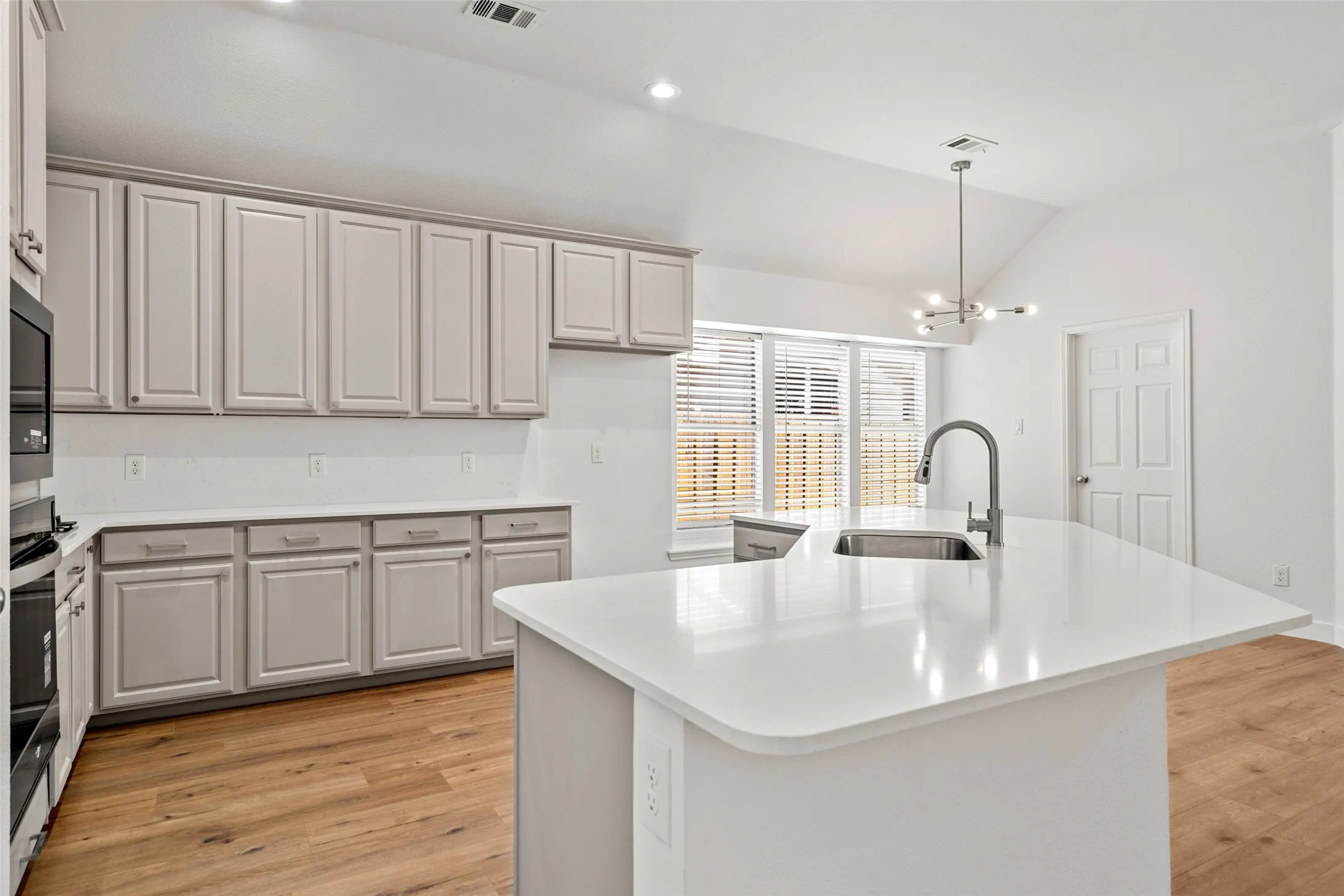 White kitchen island with an integrated stainless steel sink and gooseneck faucet