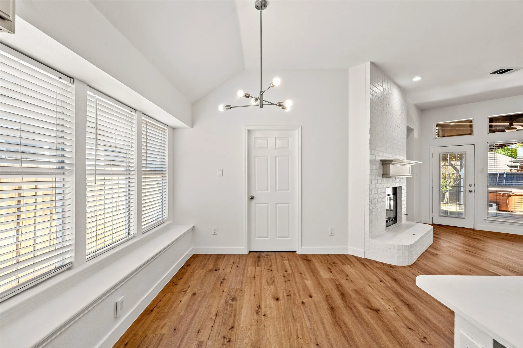 Wood-finish flooring throughout, a vaulted ceiling, and a modern linear chandelier