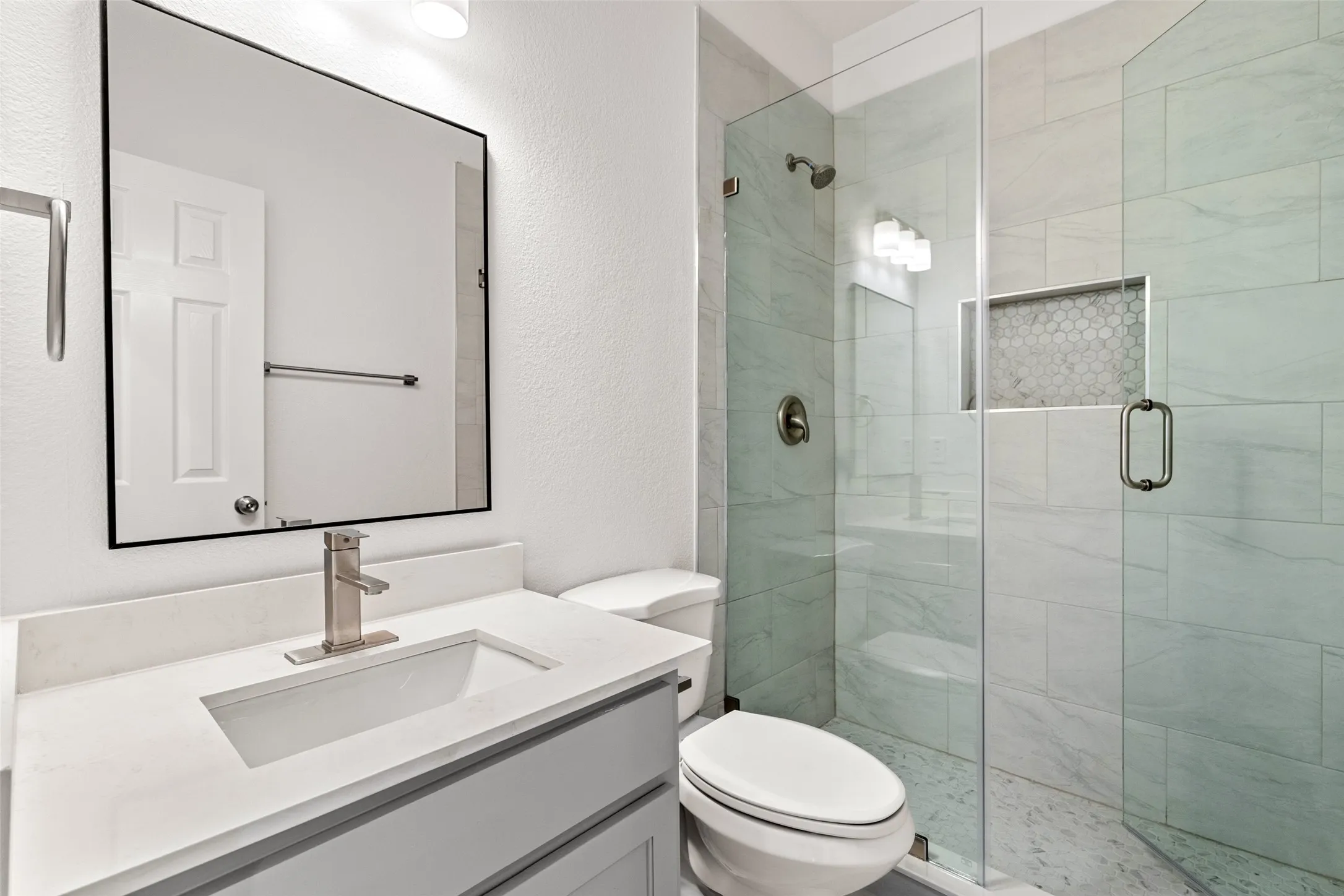 Vanity with integrated sink, brushed nickel faucet, and framed mirror