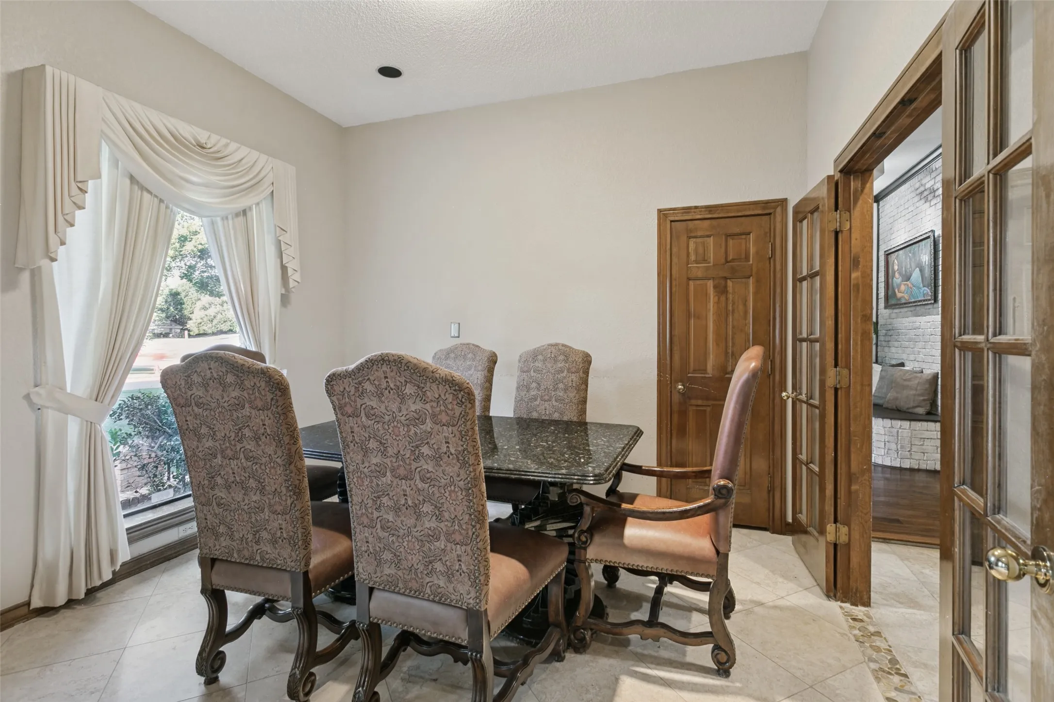 Recessed lighting with a textured ceiling, a large window with custom drapery, and wood interior doors with brass hardware enhance the dining​​‌​​​​‌​​‌‌​‌‌​​​‌‌​‌​‌​‌​​​‌​​ room