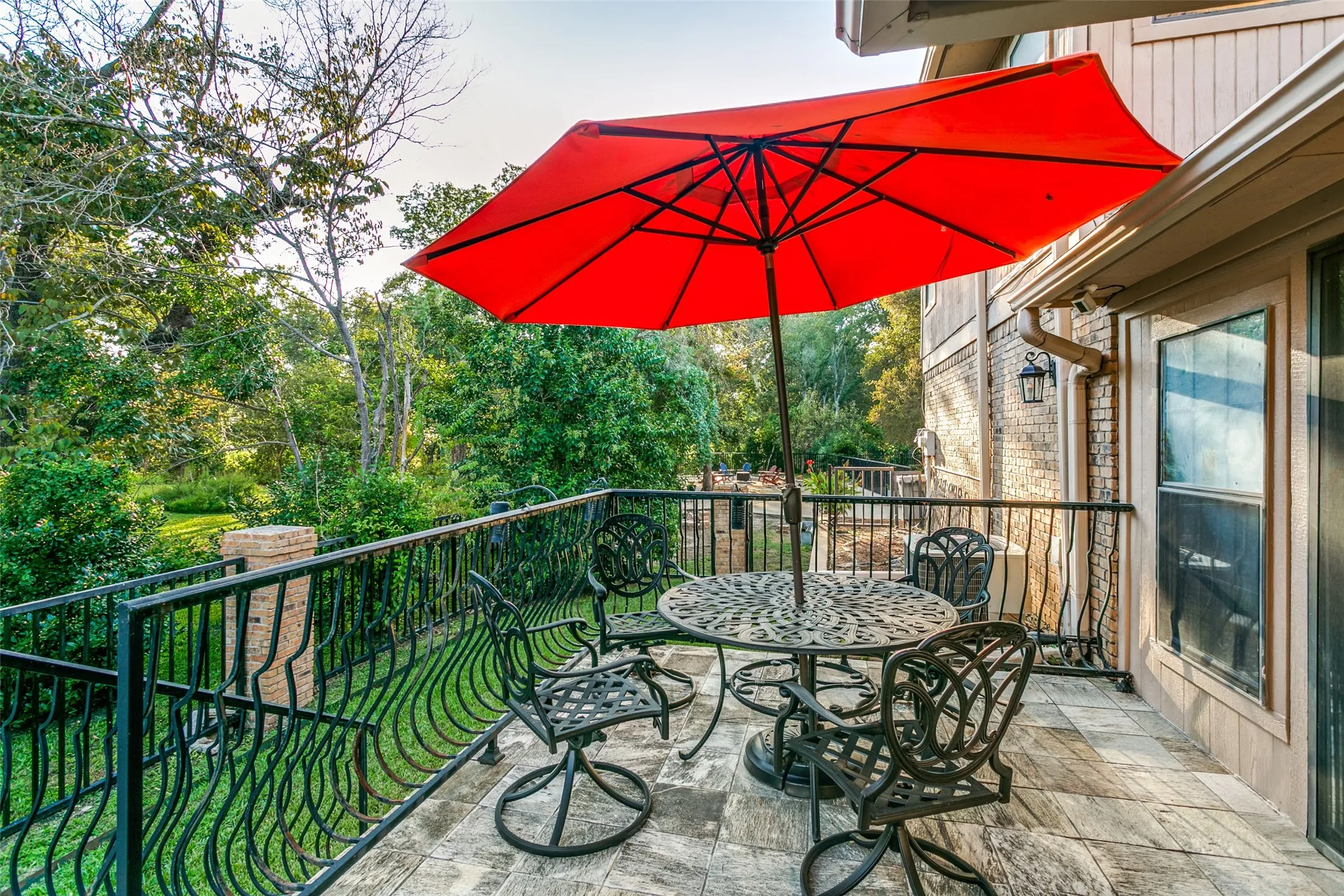 Exterior balcony featuring a tiled surface, black wrought iron railing, and a window with trim