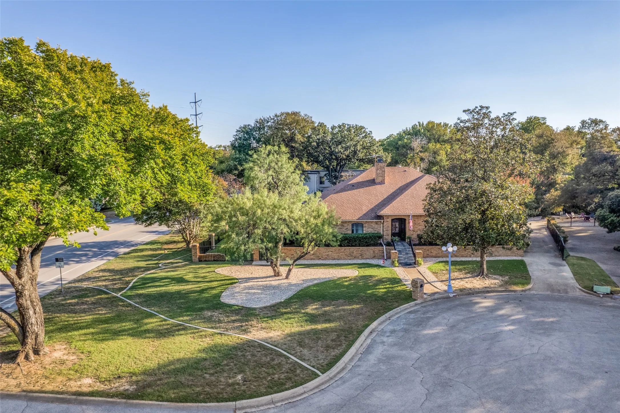 Aerial view showcases mature landscaping, paved driveway, and established trees