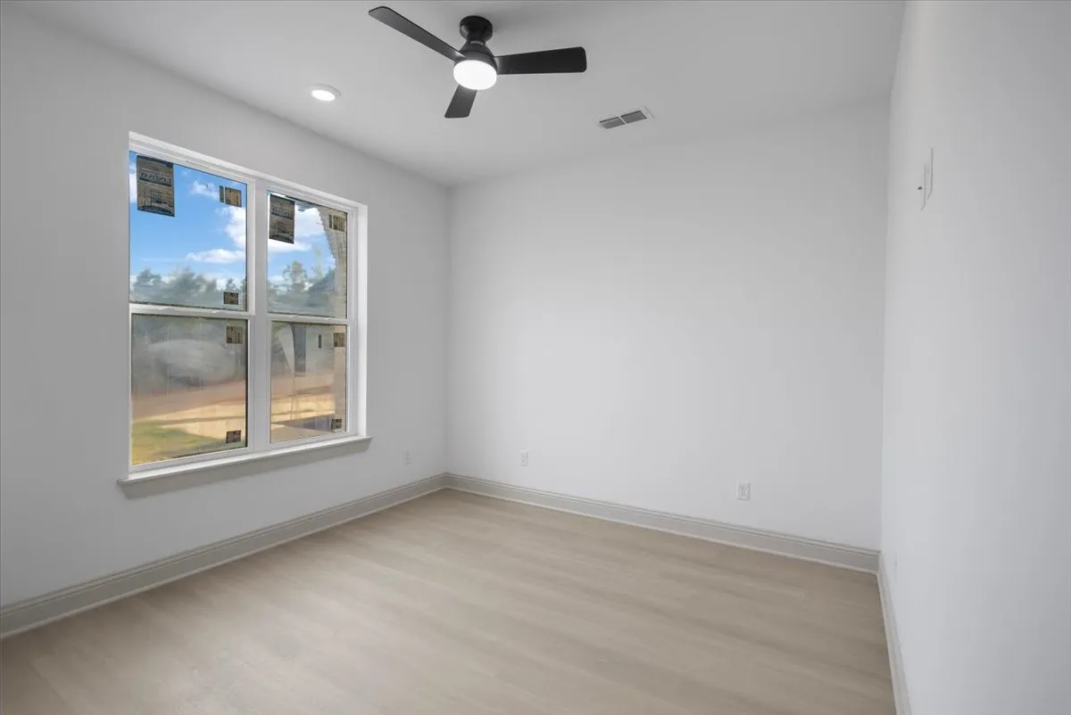 Recessed lighting, ceiling fan with integrated light, wood-finish flooring, and a large window with white trim