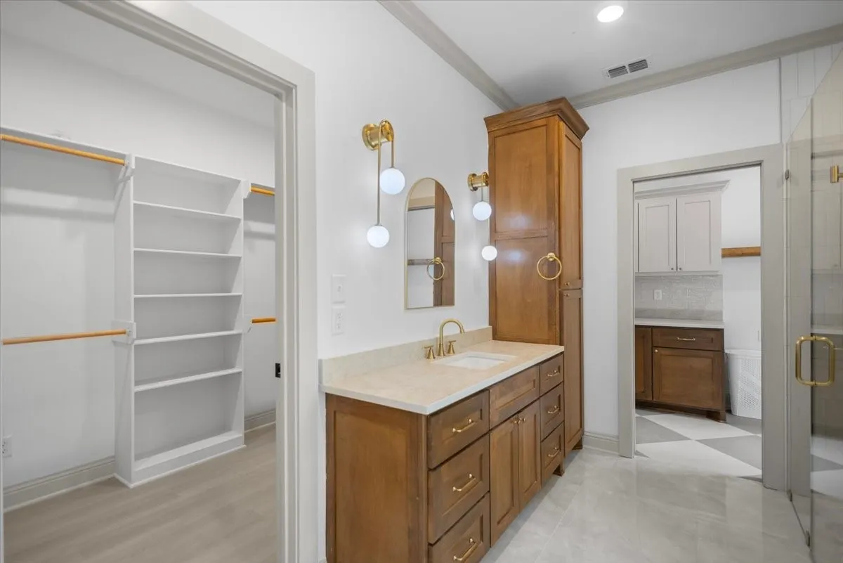 Wood-finish vanity with dual sinks, gold-tone hardware, and a light-toned countertop
