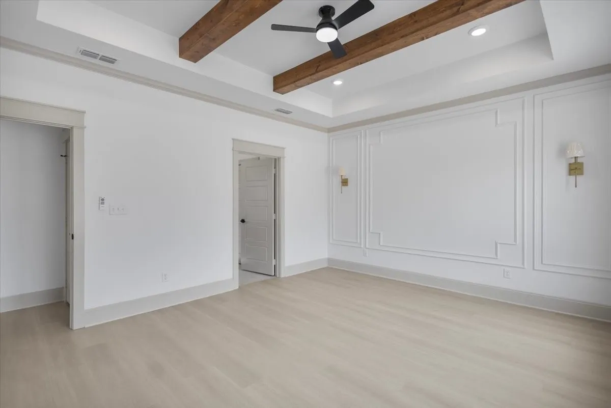 Tray ceiling with wood-finish beams, recessed lighting, and a ceiling fan