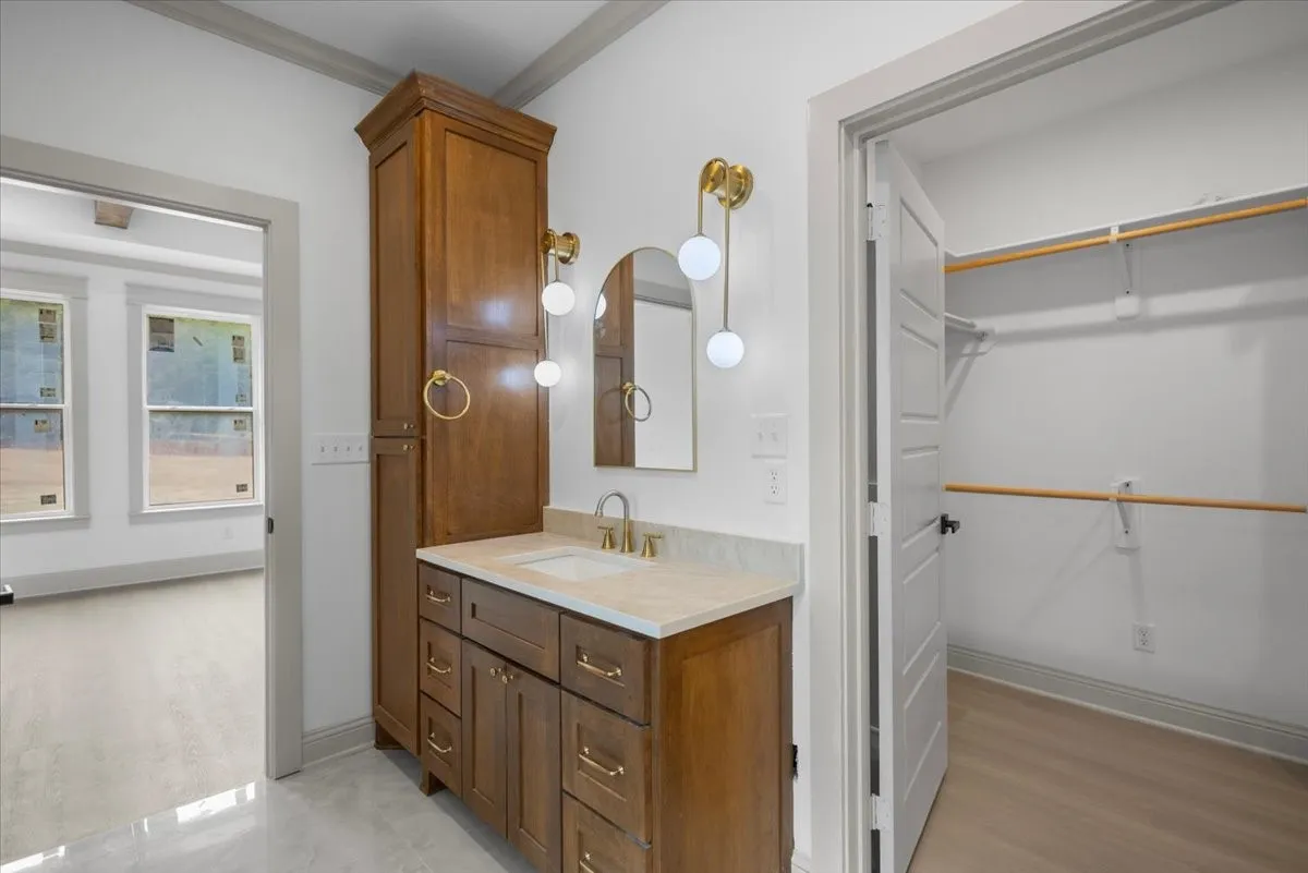 Vanity with a single basin, gold-finish faucet, and coordinating wall-mounted light fixtures