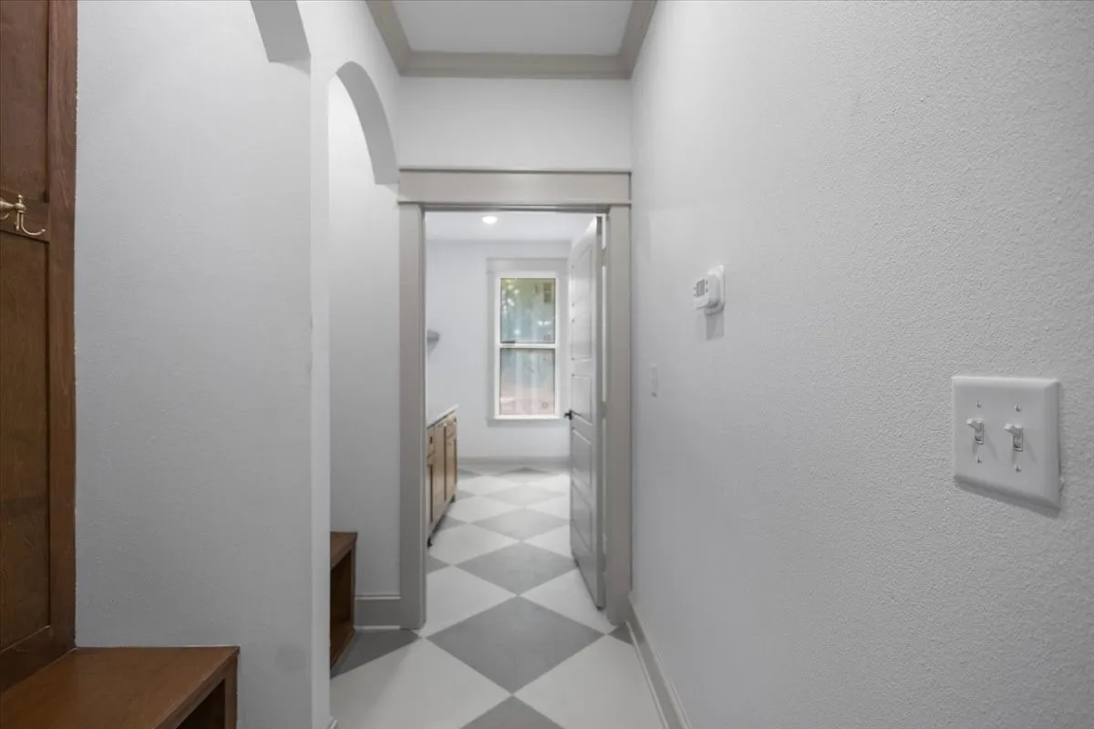 Hallway with arched entryway, built-in wooden bench, and diamond-patterned flooring