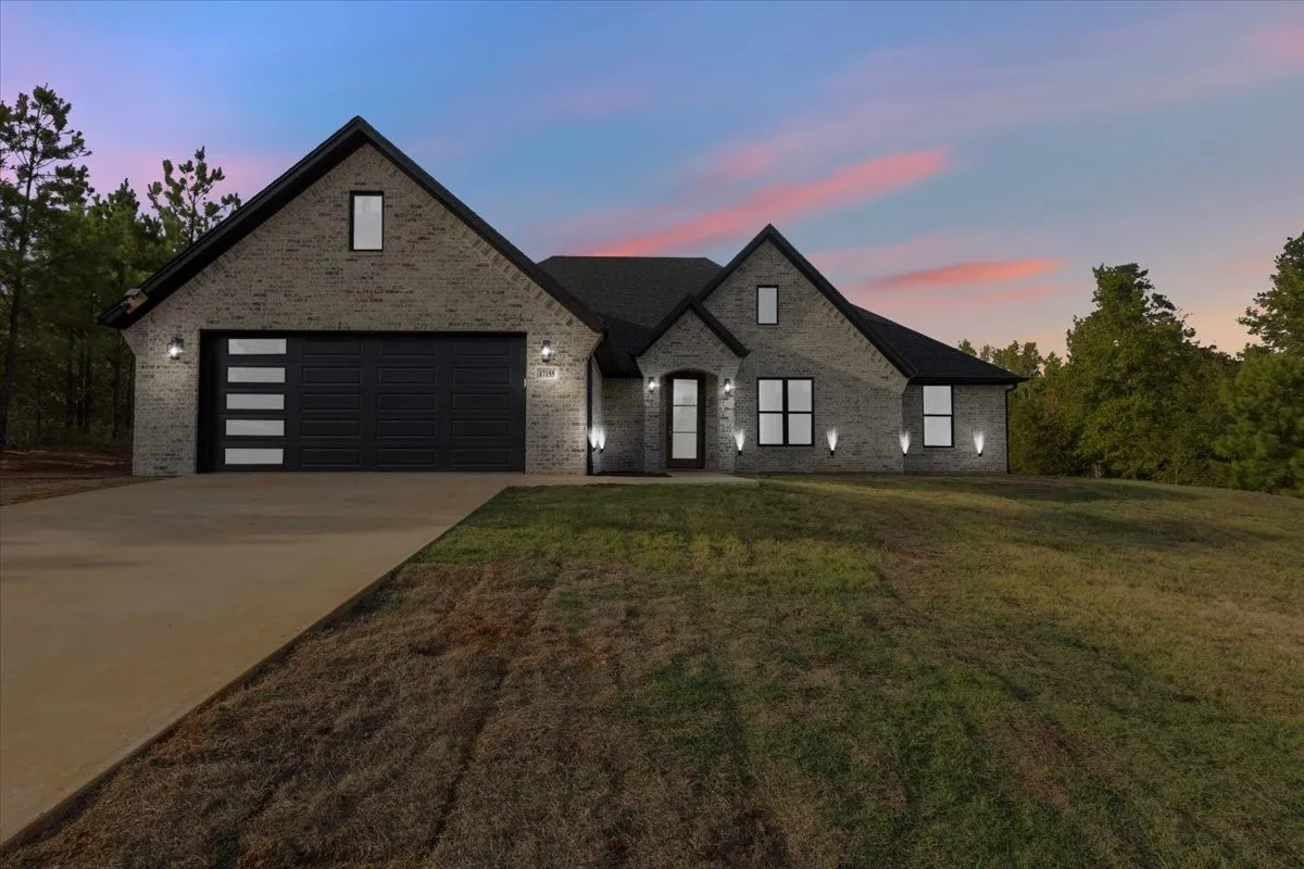 Brick exterior with a dark roofline, featuring a concrete driveway and an attached garage with a contemporary door