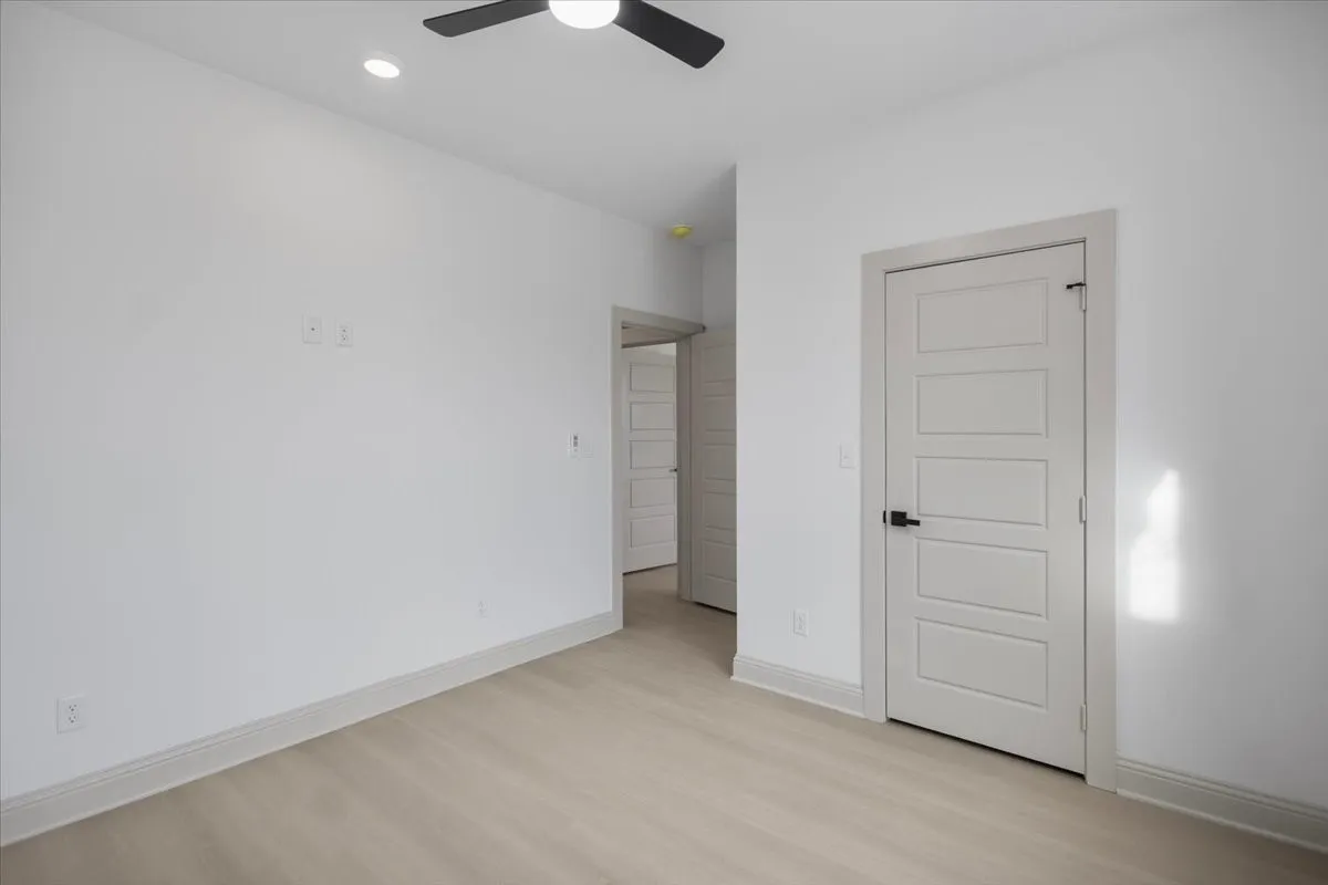 Recessed lighting, wood-finish flooring, ceiling fan, solid core door, and neutral paint palette