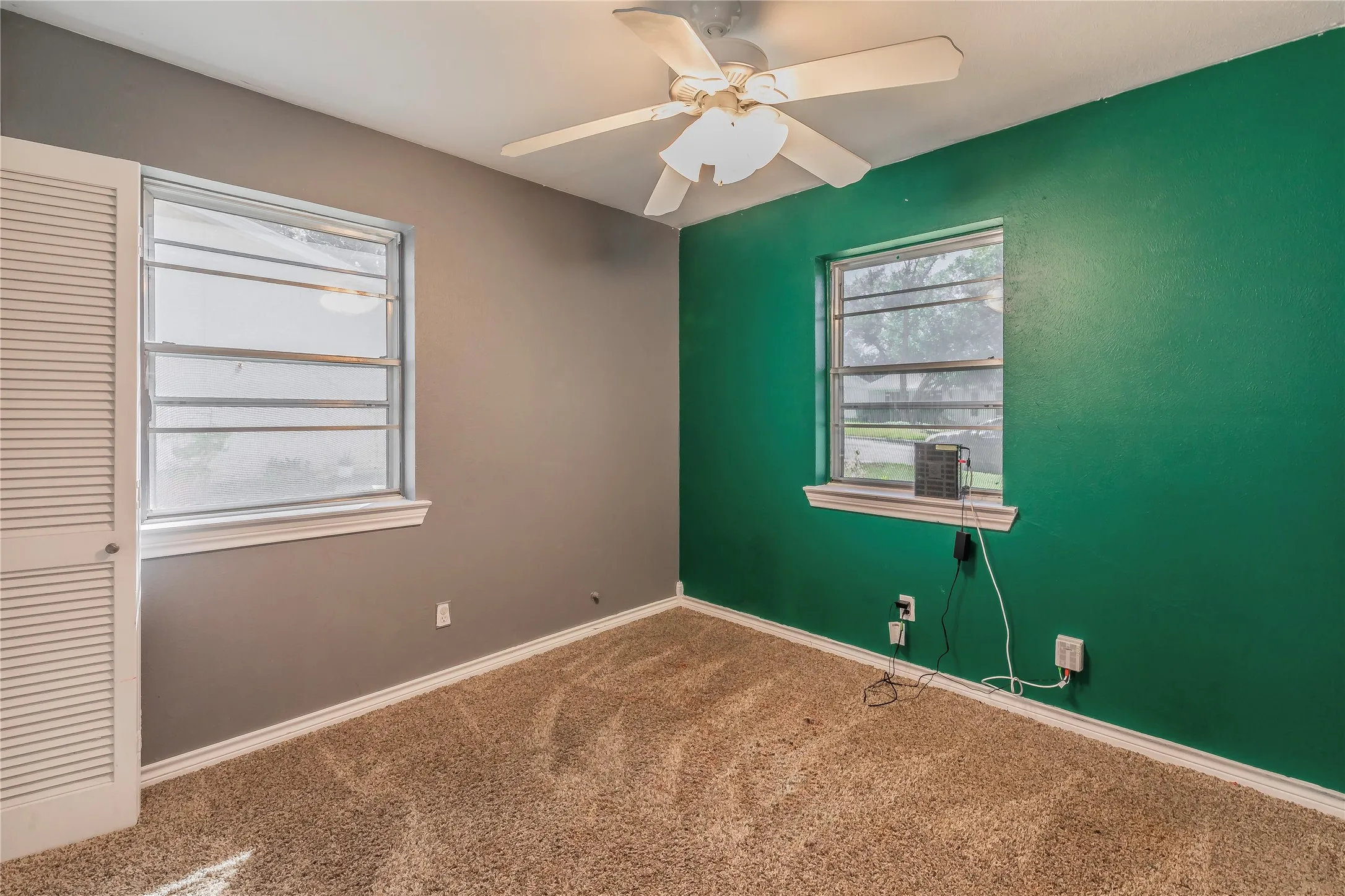 Carpet flooring, ceiling fan, and two windows with white trim