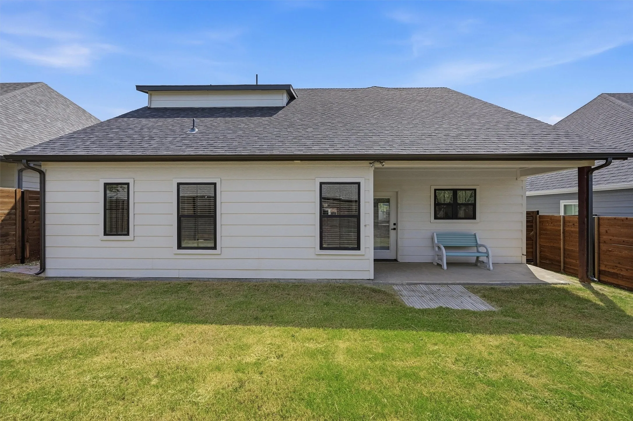 Rear exterior featuring a covered patio, concrete slab, and wood privacy fencing