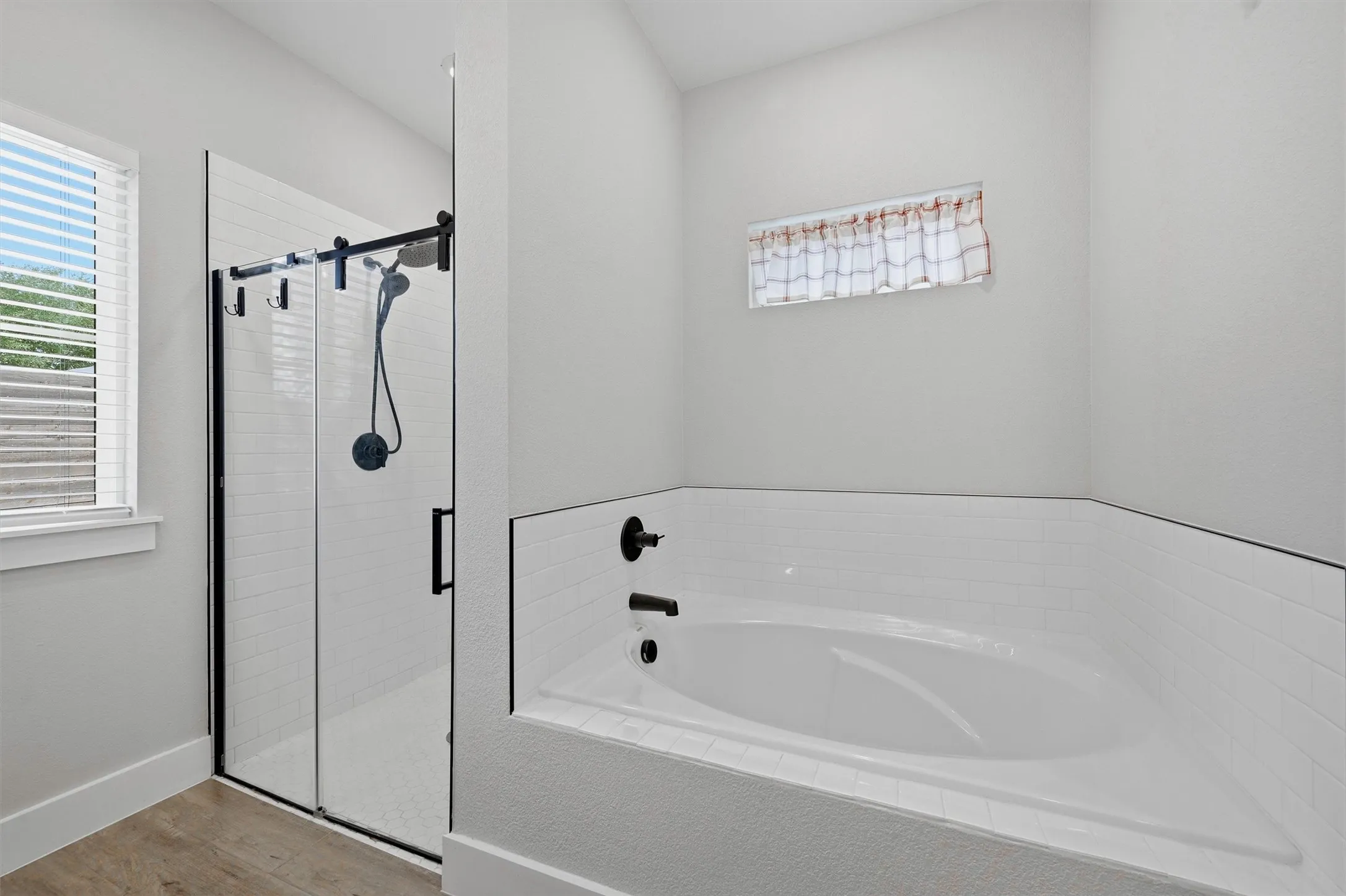 Built-in soaking tub with black fixtures, framed by subway tile