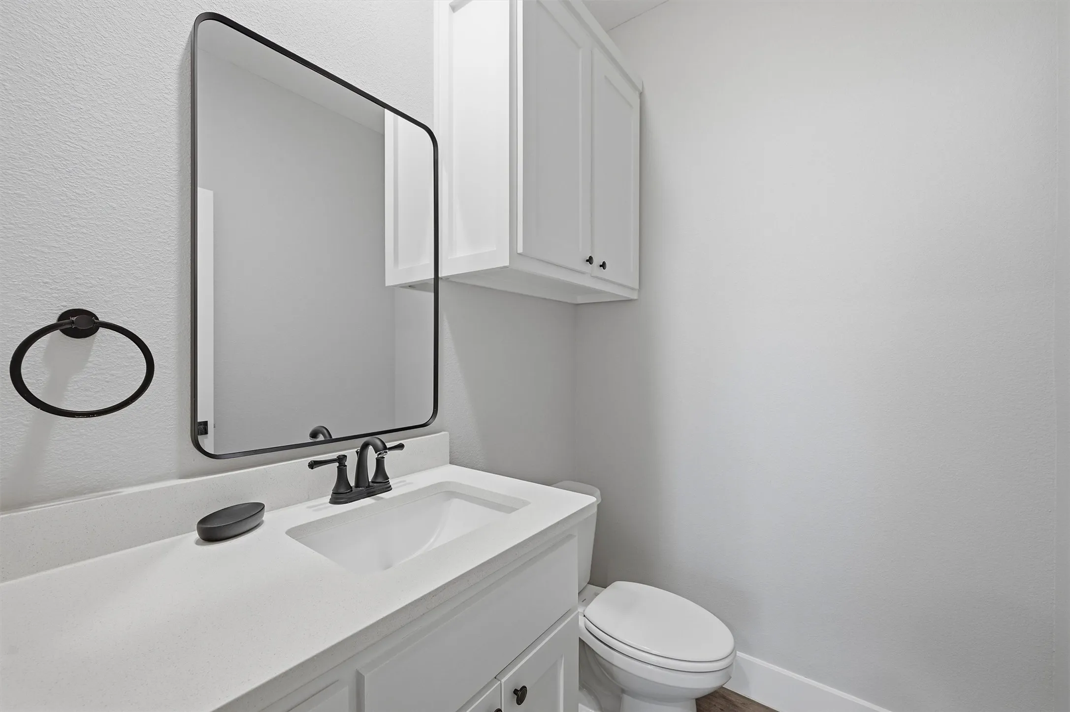 White vanity with a rectangular undermount sink, matte black faucet, and white countertop