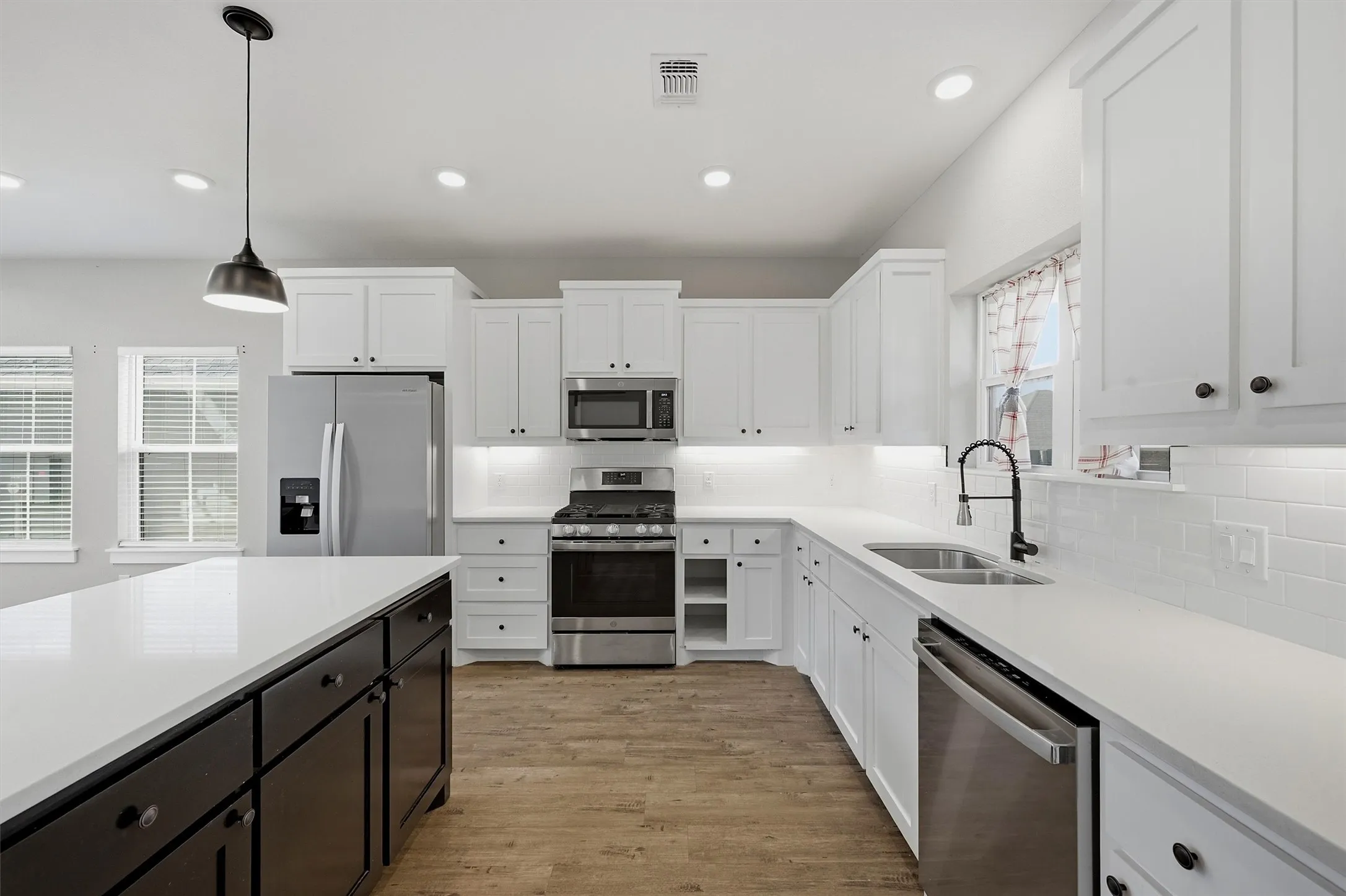 Kitchen featuring white shaker cabinetry, stainless steel appliances, white countertops, and wood-finish flooring