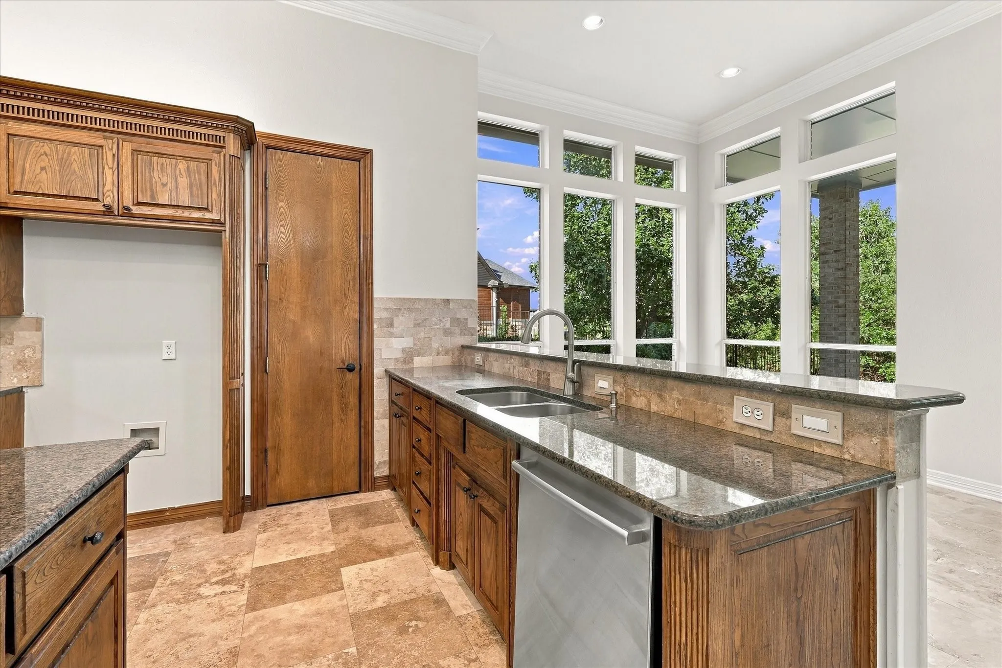 Wood cabinetry with stone countertops, integrated stainless steel dishwasher, and a dual basin sink