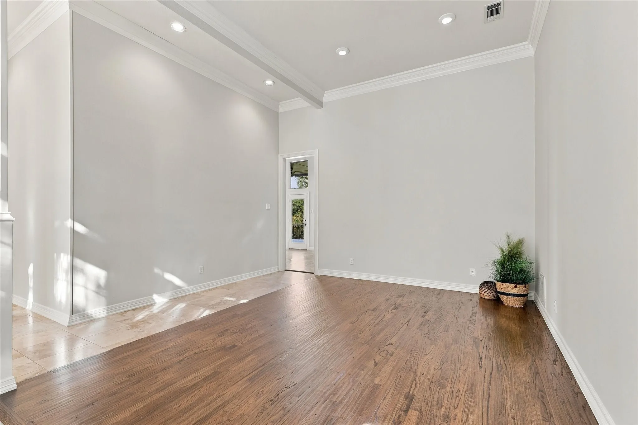 Hardwood flooring, recessed lighting, crown molding, and a paneled entry door with transom window