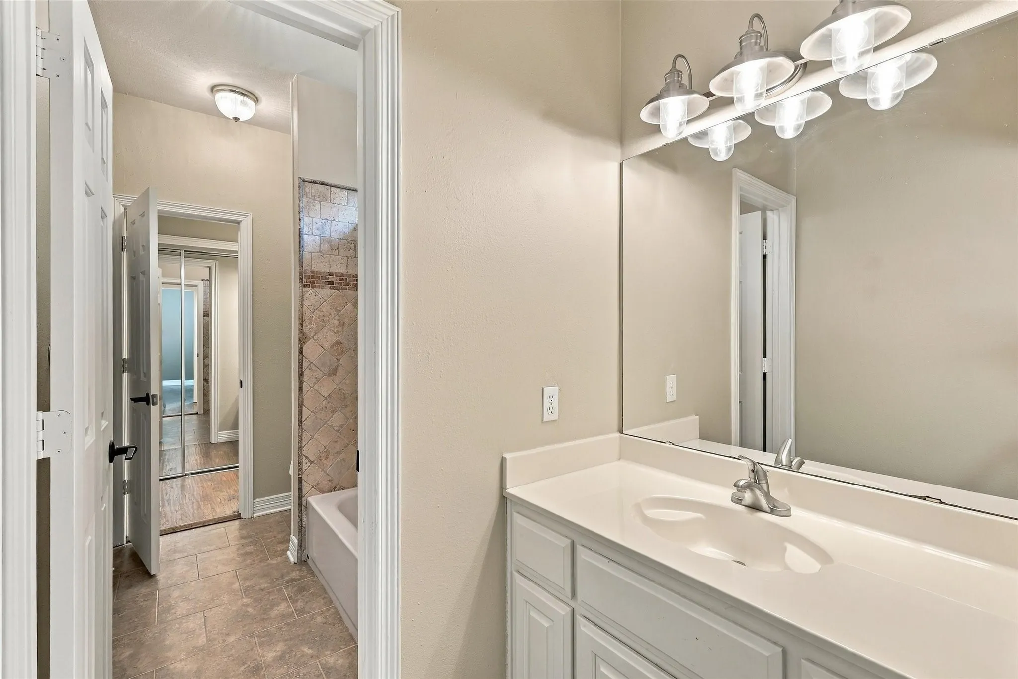 Bathroom vanity with a single basin, wall-mounted mirror, and overhead light fixture