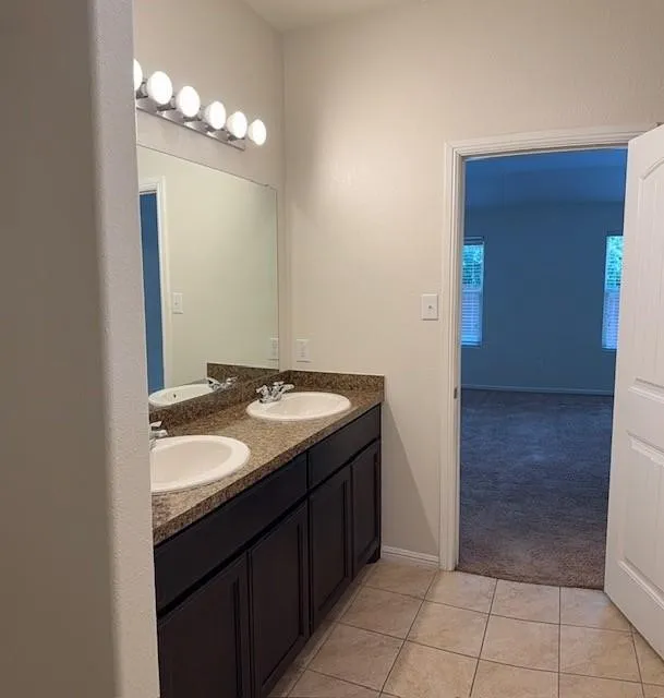 Bathroom featuring a dual vanity with a speckled countertop, undermount sinks, and dark wood cabinetry