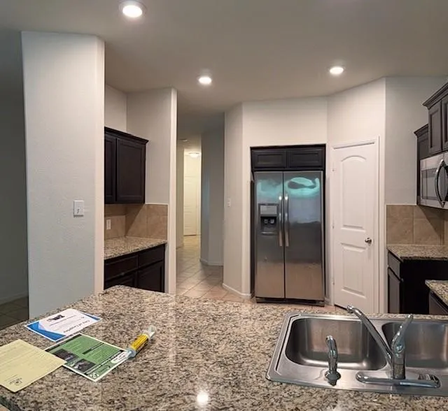Kitchen featuring recessed lighting, dark cabinetry, stainless steel appliances, a tile backsplash, and speckled countertops