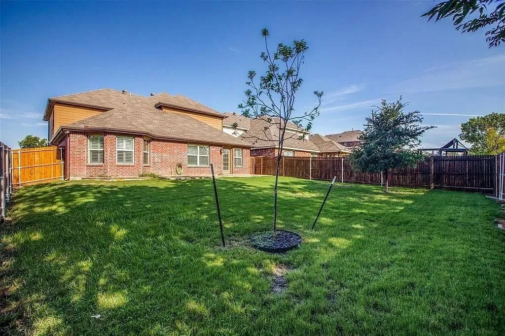 Expansive lawn area, brick exterior, multi-panel windows, and perimeter fencing