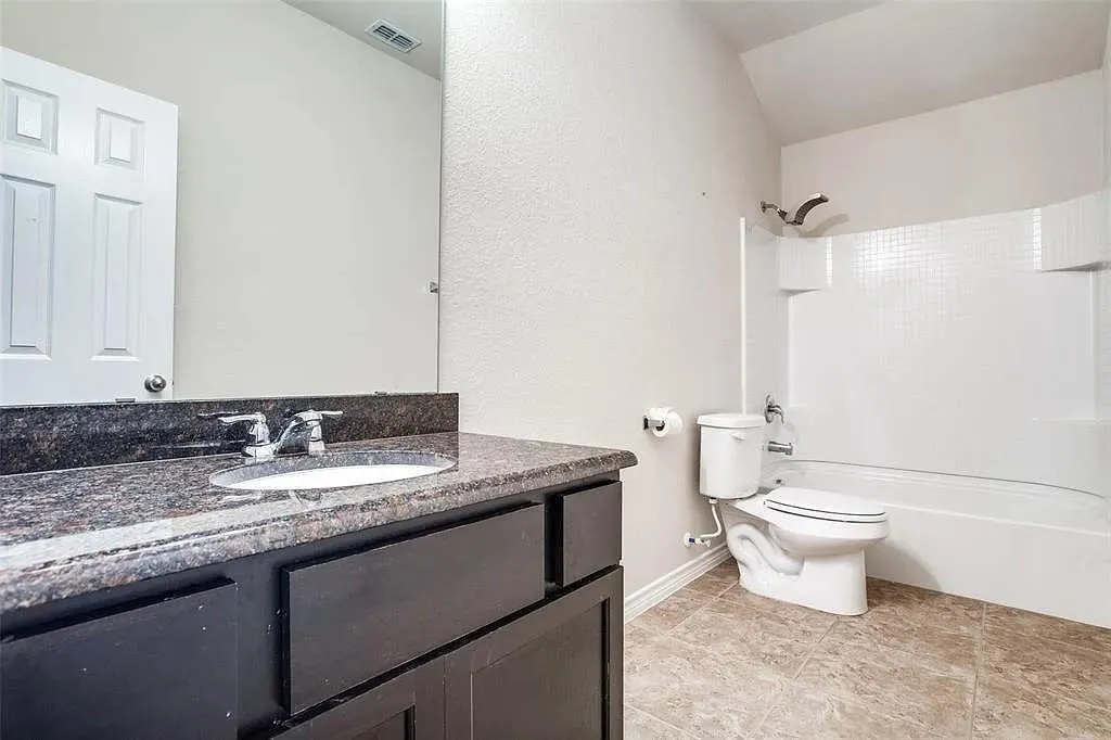 Vanity with a dark-toned countertop, undermount sink, and chrome faucet