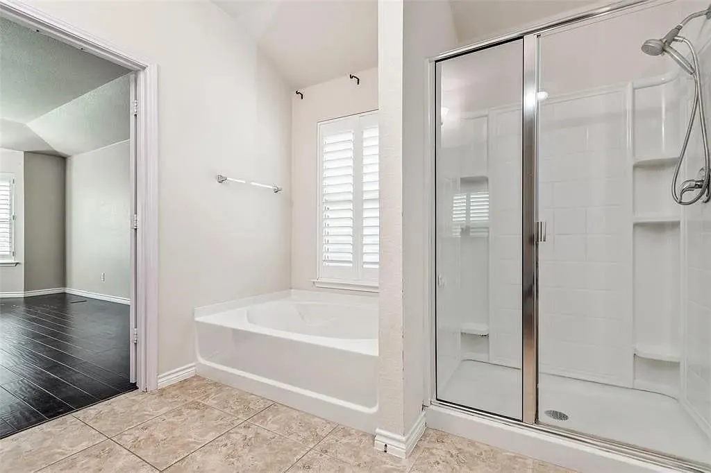Tile flooring complementing a built-in tub and a shower with glass sliding doors