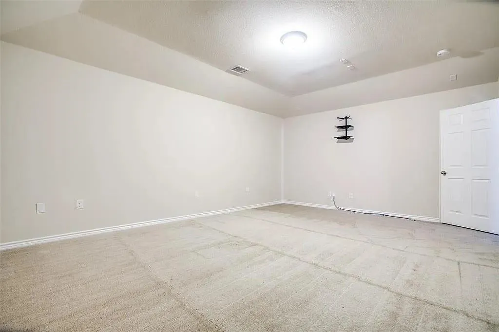 Recessed ceiling lighting, tray ceiling detail, soft carpet flooring, light neutral wall paint, and a classic paneled door