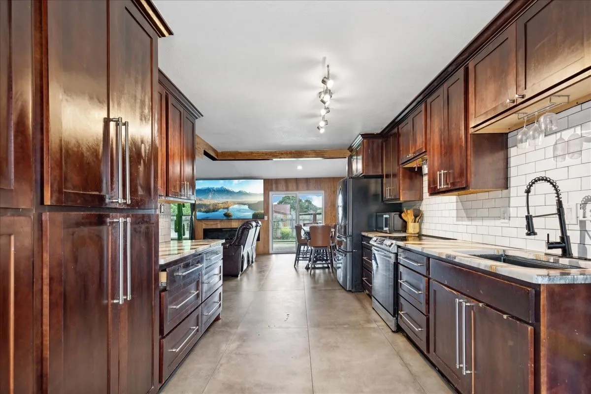 Full-height cabinetry with stainless steel hardware, stone countertops, subway tile backsplash, and a modern black gooseneck faucet