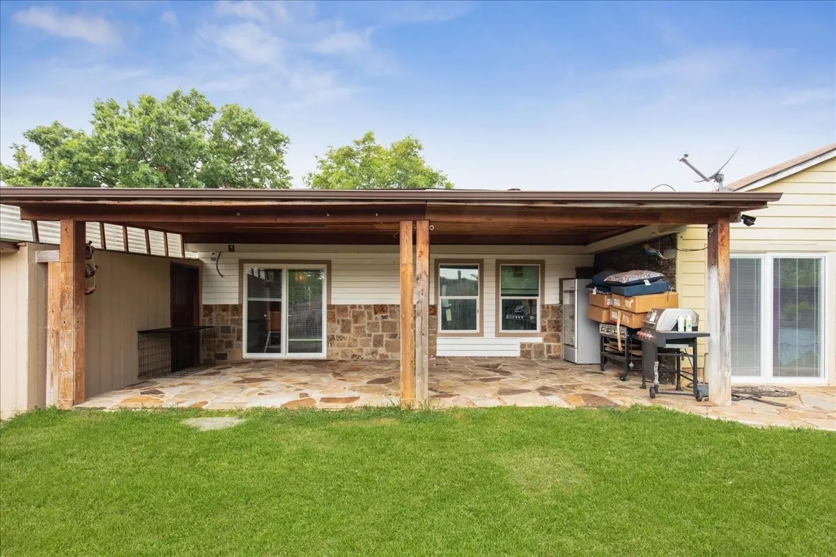 Expansive covered patio with flagstone flooring, wood support beams, and horizontal siding