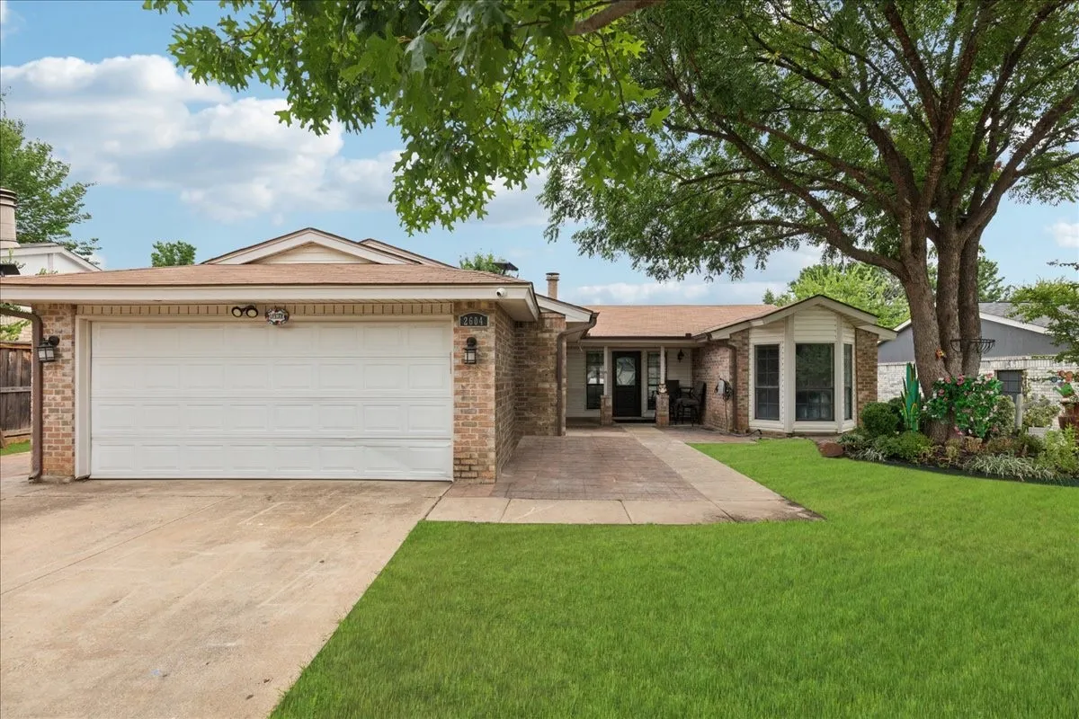 Brick exterior with a two-car garage, a concrete driveway, and a front walkway