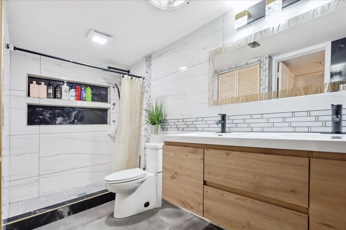 Dual vanity with wood-finish cabinetry, white countertop, and matte black fixtures