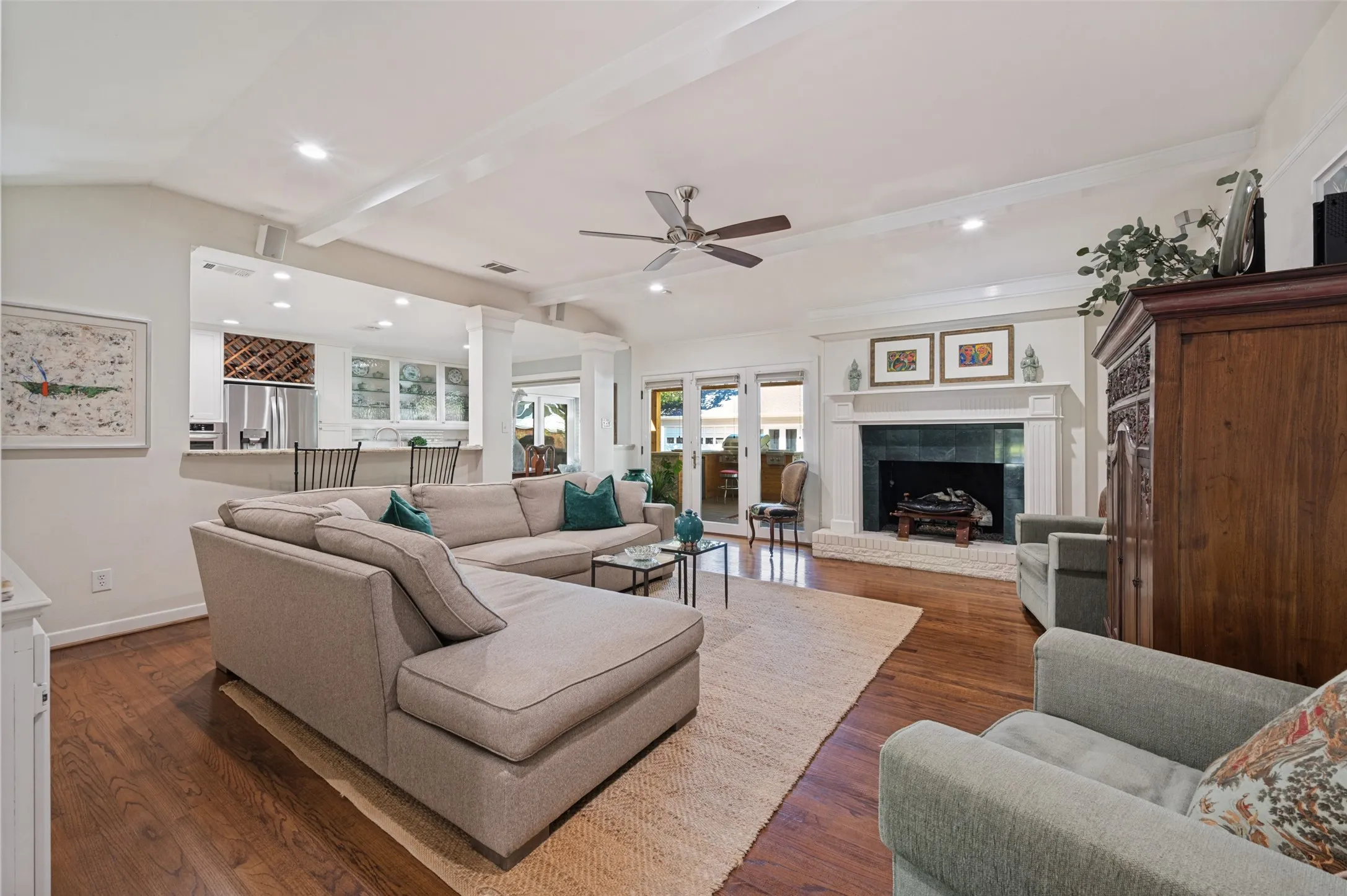 Hardwood flooring, vaulted ceiling with exposed beams, built-in fireplace with stone hearth, recessed lighting, and a ceiling fan