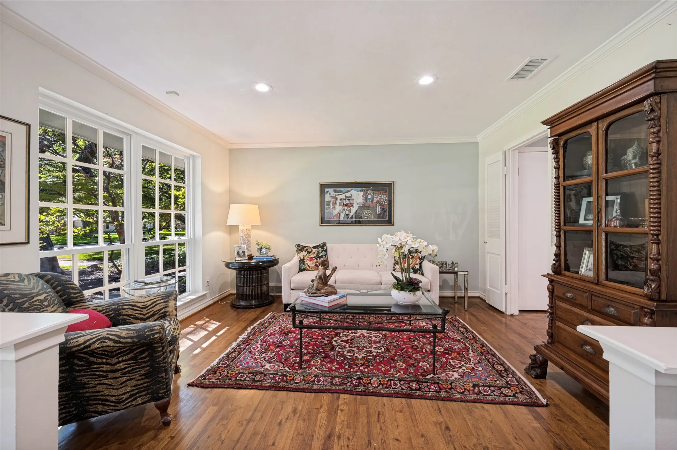 Hardwood flooring, crown molding, recessed lighting, and a large multi-pane window